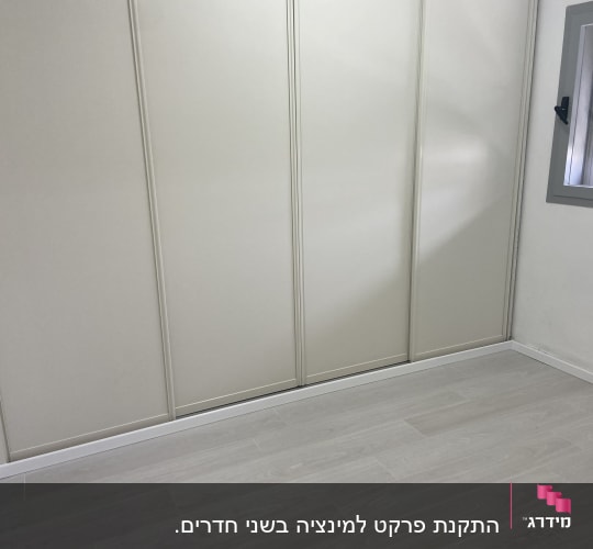 רצפת פרקט עץ בהירה בחדר עם קיר לבן